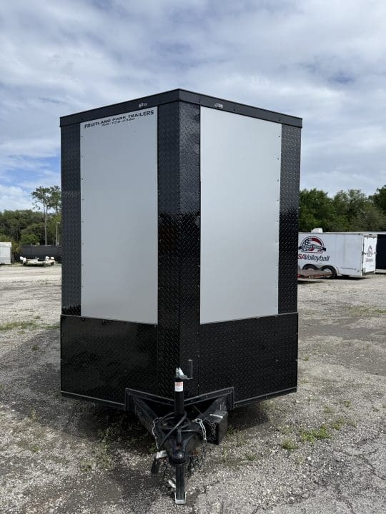Black utility trailer on gravel lot