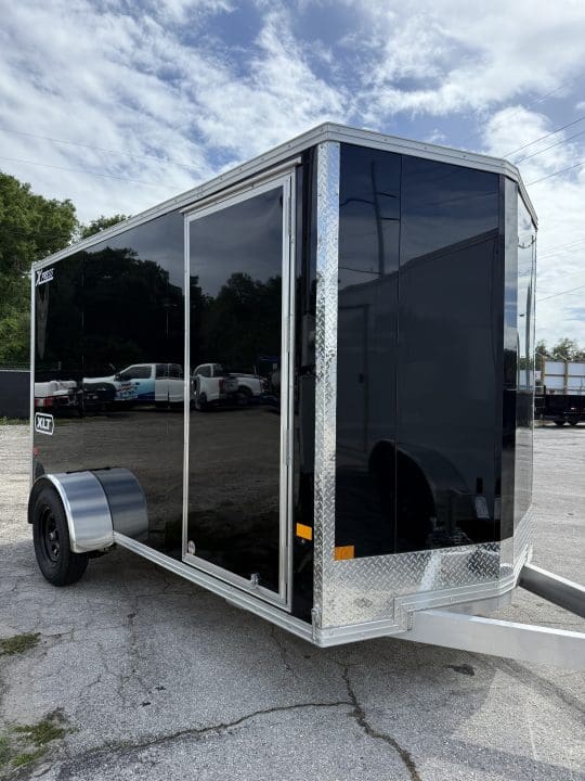 Black enclosed cargo trailer in parking lot.